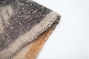 Close-up of thick bouclé knit fabric with colorful tweed flecks and soft fringe edge