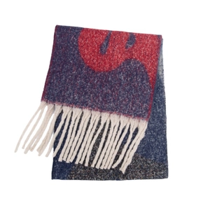 Détail d'une écharpe en maille jacquard aux motifs abstraits et franges blanches