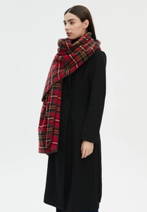 Close-up showing the draped layers of a red and black plaid scarf on a wool coat