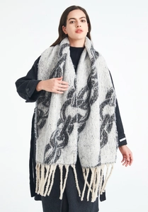 Macro detail of the soft knit texture and long chain pattern fringes on the winter shawl