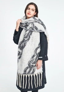 Detail of thick knit scarf with black chain patterns and long fringe on black cashmere coat