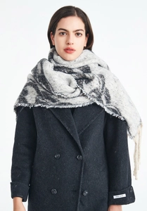 Detailed view of women's thick winter shawl featuring marble jacquard and tassel edges