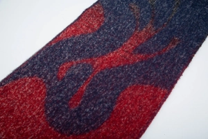 Détail de l'écharpe en maille douce à motifs géométriques rouge et bleu avec des franges