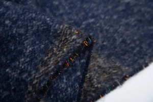 Détail macro de tricot bouclé bleu marine avec fibres colorées et texture moelleuse