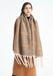 Detailed close-up of thick grey and orange plaid knit scarf with long decorative tassels
