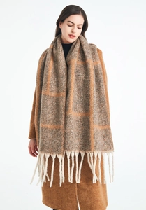Close-up of thick plaid knit scarf with long fringe details in warm earth tones