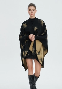 Detail eines Strick-Capes mit schwarz-gelbem Blattmuster und seitlichem Schlitz