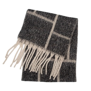 Close-up of thick boucle yarn scarf featuring dark grey and off-white plaid pattern and tassels