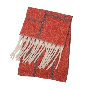 Detail of orange checkered scarf with soft knit texture and white fringe tassels