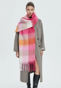 Detail of colorful rainbow plaid mohair scarf texture with thick tassels on grey coat