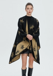 Detail of black knit shawl featuring golden ginkgo leaf patterns and split hem design