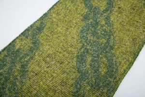 Close-up of thick bouclé yarn scarf with green chain pattern and tassel fringe details