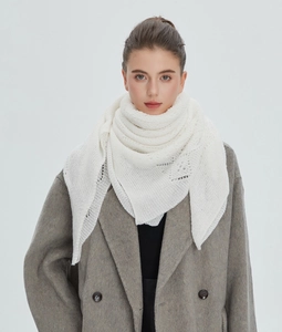 Detailed view of white knitted shawl featuring delicate hollow-out patterns and soft texture