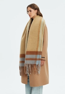 Detailed view of handmade label on wool coat sleeve with thick khaki plaid fringe scarf