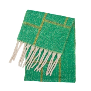 Close-up of thick cream fringes on a plush green and yellow plaid knit scarf