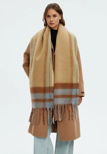 Detail of thick khaki plaid scarf featuring soft mohair texture and long tassel trim