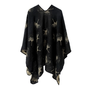 Nahaufnahme goldener Ginkgoblatt-Muster auf einem schwarzen Strickponcho-Wickelschal