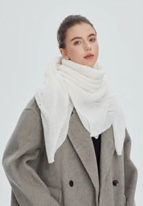 Detail of white hollow-out knit shawl featuring delicate crochet texture on wool coat
