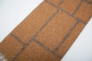 Detailed view of camel and grey check pattern on soft mohair style fringed scarf