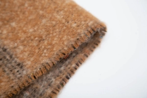 Detail of soft mohair-like jacquard scarf with melange knit texture and whipstitch edge
