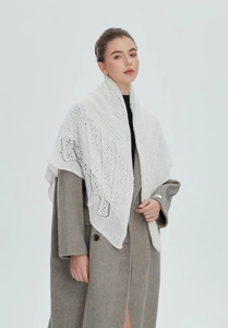 Detailed view of elegant white lace knitted shawl over a long wool coat