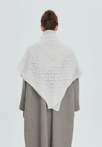 Detail of white hollow knit shawl showing intricate geometric patterns on a grey wool coat