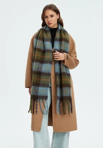 Close-up of thick blue and green plaid scarf texture with long fringe and handmade label