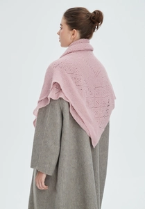 Detail of pink hollow knit shawl layered over a dark grey wool coat with geometric texture
