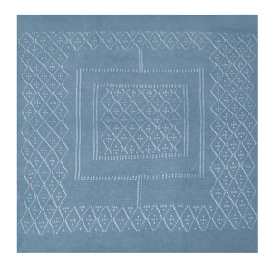 Close-up of blue knitted shawl featuring white geometric diamond patterns and textures