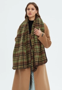 Close-up of thick green plaid scarf texture and handmade label with camel coat