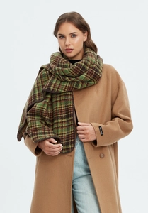 Detail of green plaid winter scarf paired with a beige coat and handmade sleeve label