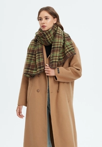 Close-up of thick green plaid scarf paired with a camel wool coat in winter setting