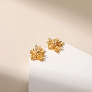 18K gold plated leaf earrings with sparkling zircon inlay on white podium