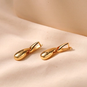 Polished 18K gold teardrop earrings with elegant water drop pendants on beige fabric