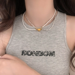 Double-layer pearl and silver bead necklace with a gold heart pendant on a female model