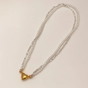 Detail of double-layer necklace with white pearls, silver beads and gold heart pendant
