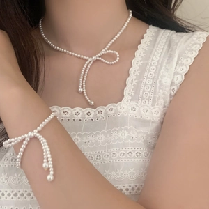 Detail von elegantem Perlen-Schleifen-Halsketten- und Armband-Set auf Spitze