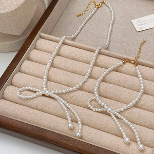 Elegantes Set aus Perlen-Halskette und Armband mit Schleife auf Schmucktablett