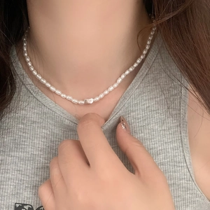 Elegante Perlenkette mit silbernem Herzanhänger an Model in geripptem Oberteil