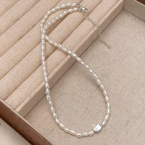Detail einer eleganten Perlenkette mit Silberanhänger auf einem beigen Schmucktablett