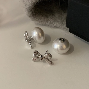 Silver bow pearl earrings featuring polished liquid metal texture and glossy white pearls
