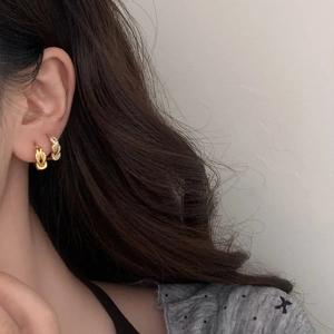 Gold twist knot earring set with zirconia studs on model for a layered look