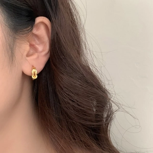 Elegant gold knotted hoop earrings with a polished finish worn by a model