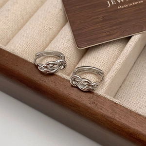 Macro detail of silver knot hoop earrings on a velvet jewelry display tray