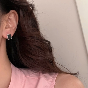 Minimalist square black stud earrings with silver frame worn by a model in soft lighting