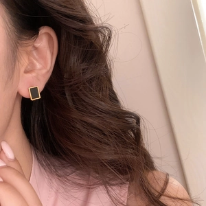 Close-up of elegant gold earrings with black rectangular inlay on ear for office wear