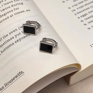 Detail of silver geometric hoop earrings with black inlay on a vintage book background
