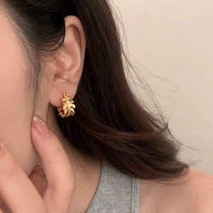 Gold leaf shaped hoop earrings with white zircon crystals shown on model ear