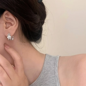 Detailed view of silver lace-patterned earrings with zircon on model's ear