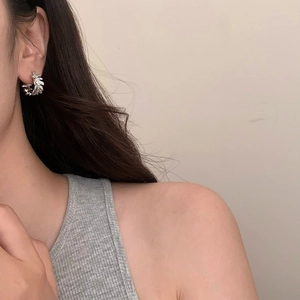 Close-up of silver irregular lace earrings with textured leaf pattern worn by a model